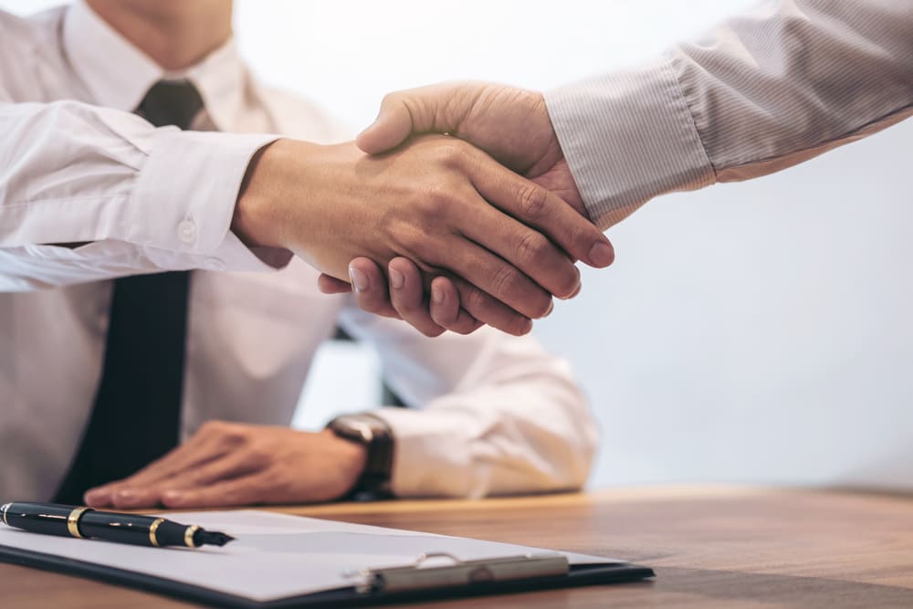 courtier client se serrant la main après avoir signé des documents contractuels.