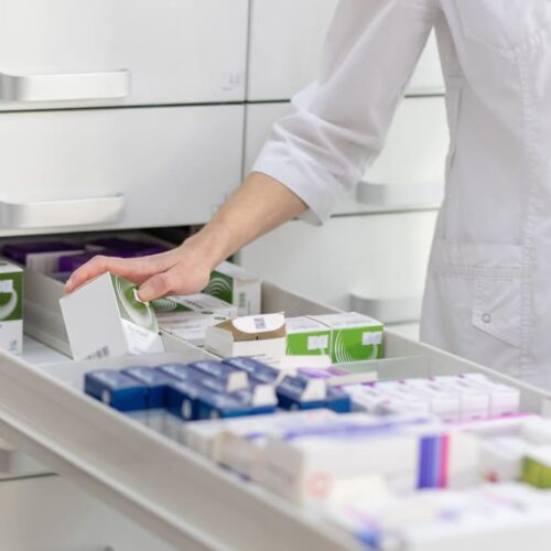 Pharmacien qui recherche une boite de médicament dans le tiroir d'une pharmacie
