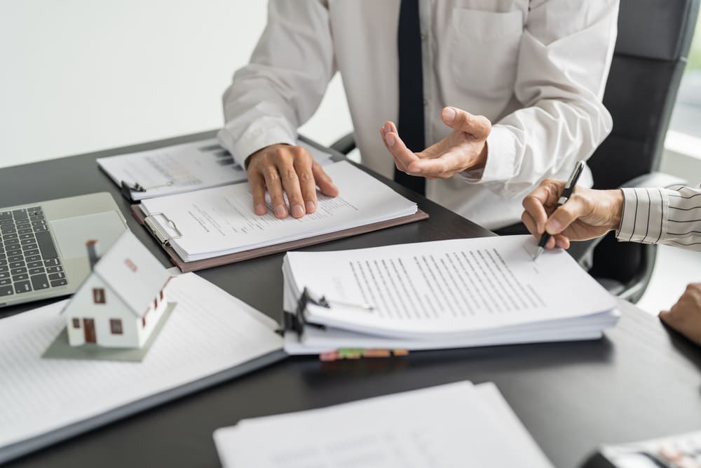 deux hommes entrain de signer des contrats pour une acquisition immobilière